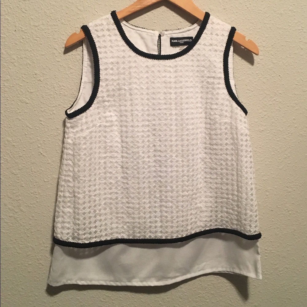 White sleeveless blouse with black trim.